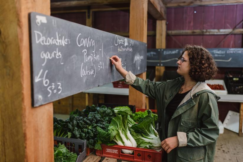 A woman writing on a chalk board at farmers market